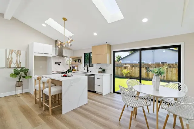 a kitchen with a table chairs stove and white cabinets