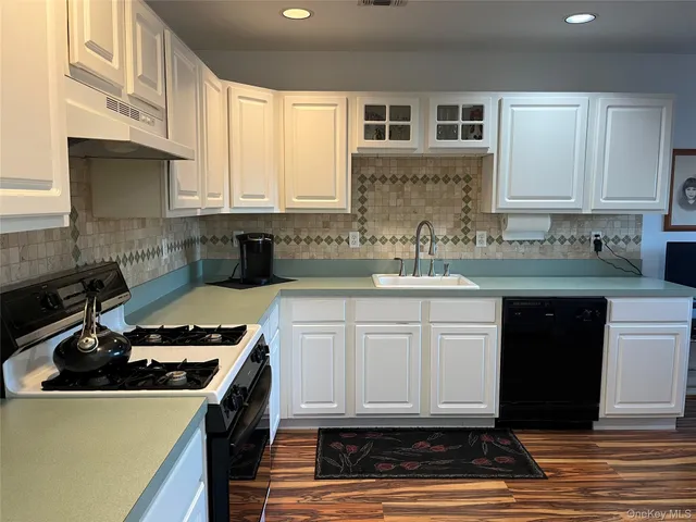 a kitchen with granite countertop a sink a stove and cabinets