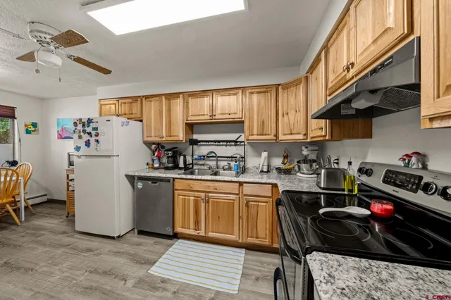 a kitchen with stainless steel appliances granite countertop a refrigerator stove top oven a sink and dishwasher