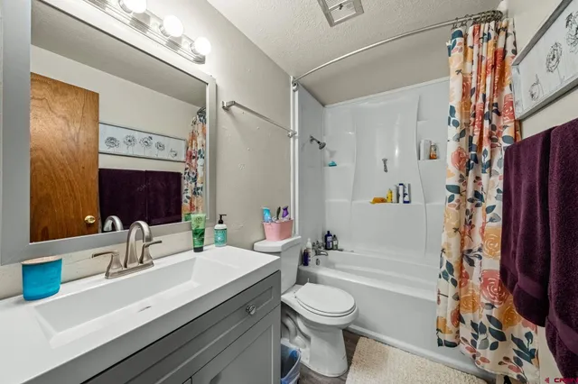 a bathroom with a granite countertop sink toilet a mirror a vanity and shower