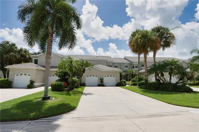 front view of house with a yard and palm trees