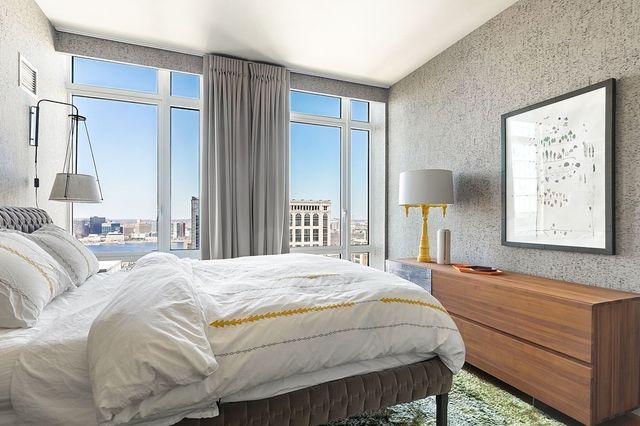 a bedroom with a bed painting on wall and a large window