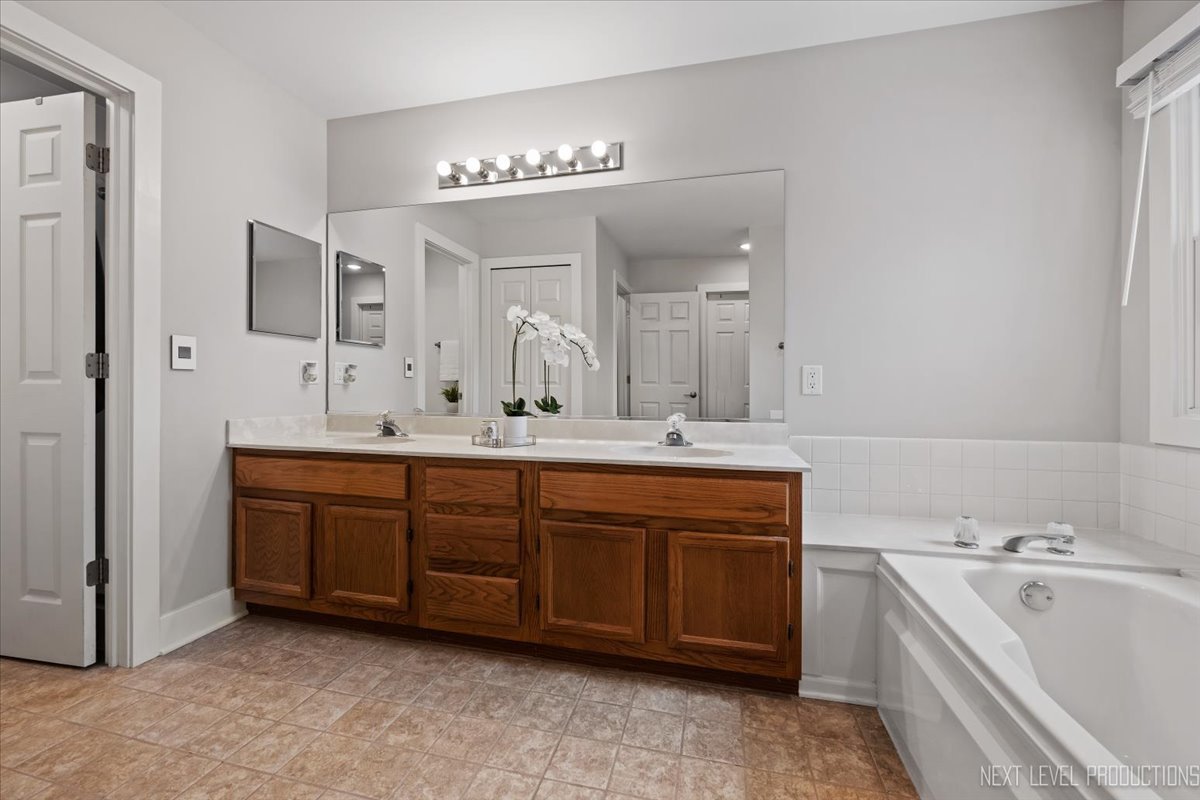 1257 Rhodes Lane Naperville, IL 60540 - Photo 17 of 24 a spacious bathroom with a double vanity sink mirror and bathtub