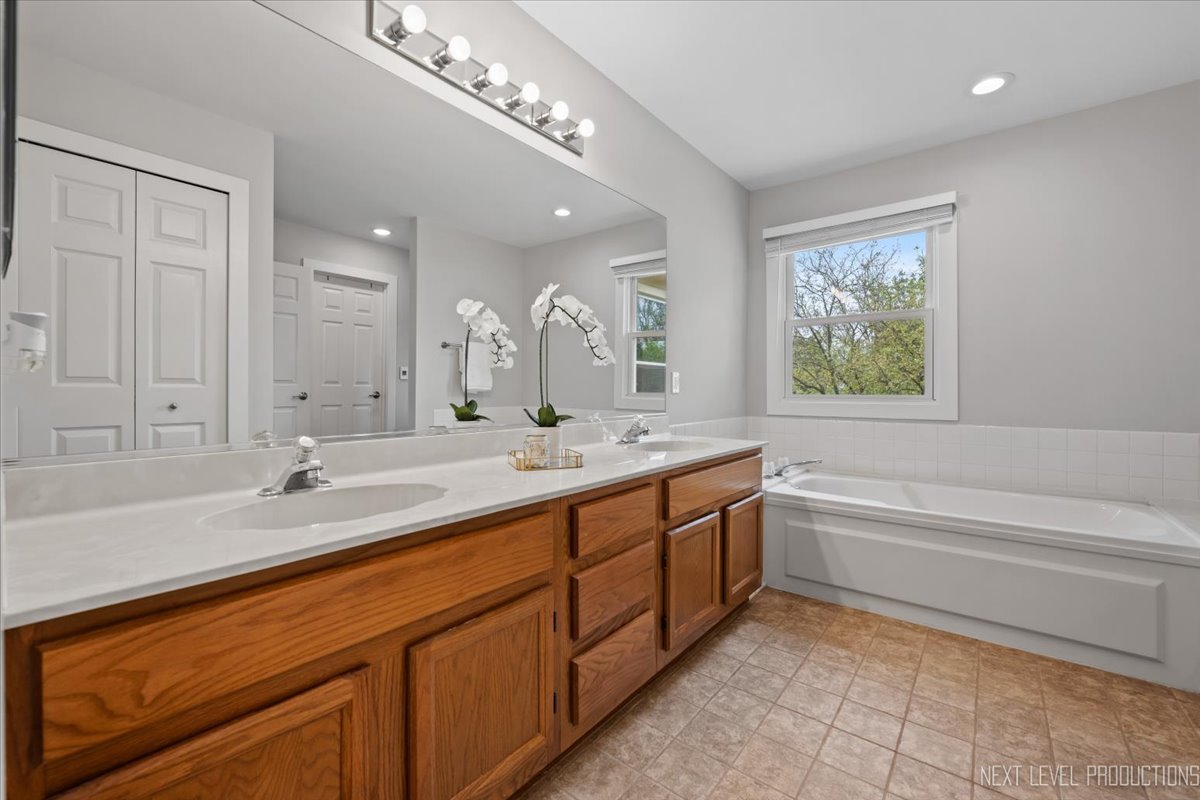 1257 Rhodes Lane Naperville, IL 60540 - Photo 18 of 24 a spacious bathroom with a double vanity sink a mirror and a bathtub