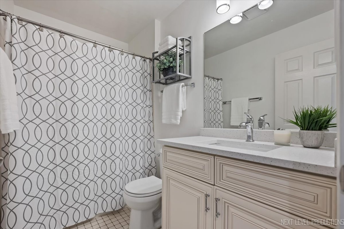 1257 Rhodes Lane Naperville, IL 60540 - Photo 21 of 24 a bathroom with a sink a toilet and shower curtain