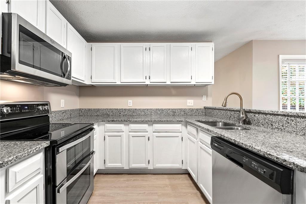 2065 Arbor Forest Drive Southwest Marietta, GA 30064 - Photo 7 of 15 a white kitchen with granite countertop a stove top oven microwave and cabinets