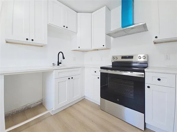 a kitchen with white cabinets and appliances