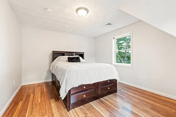 a bedroom with a bed and wooden floor