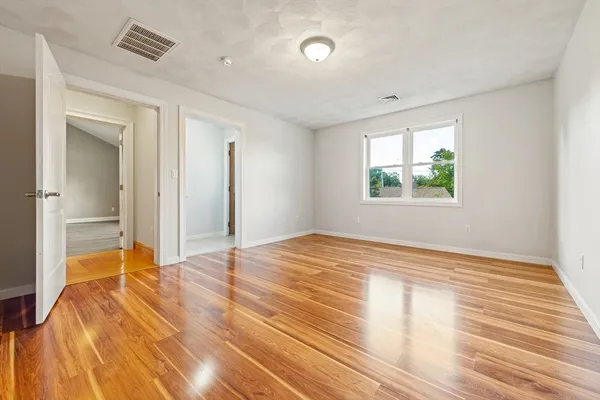 a view of empty room with wooden floor