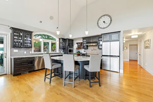 a kitchen with stainless steel appliances kitchen island granite countertop a table chairs stove and cabinets