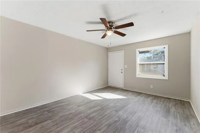 a view of an empty room with wooden floor and a window