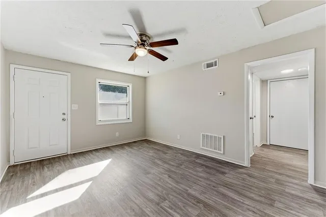 a view of an empty room with wooden floor and a window