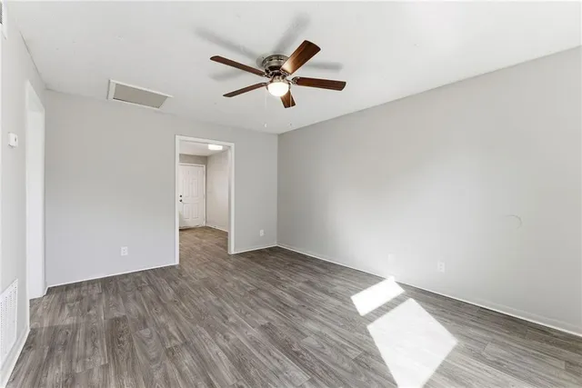 an empty room with wooden floor fan and windows