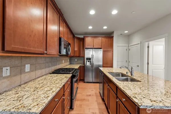 a kitchen with stainless steel appliances granite countertop sink stove refrigerator and cabinets