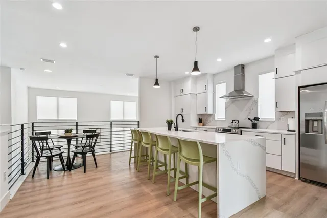 a kitchen with stainless steel appliances granite countertop a dining table chairs stove refrigerator and wooden floor