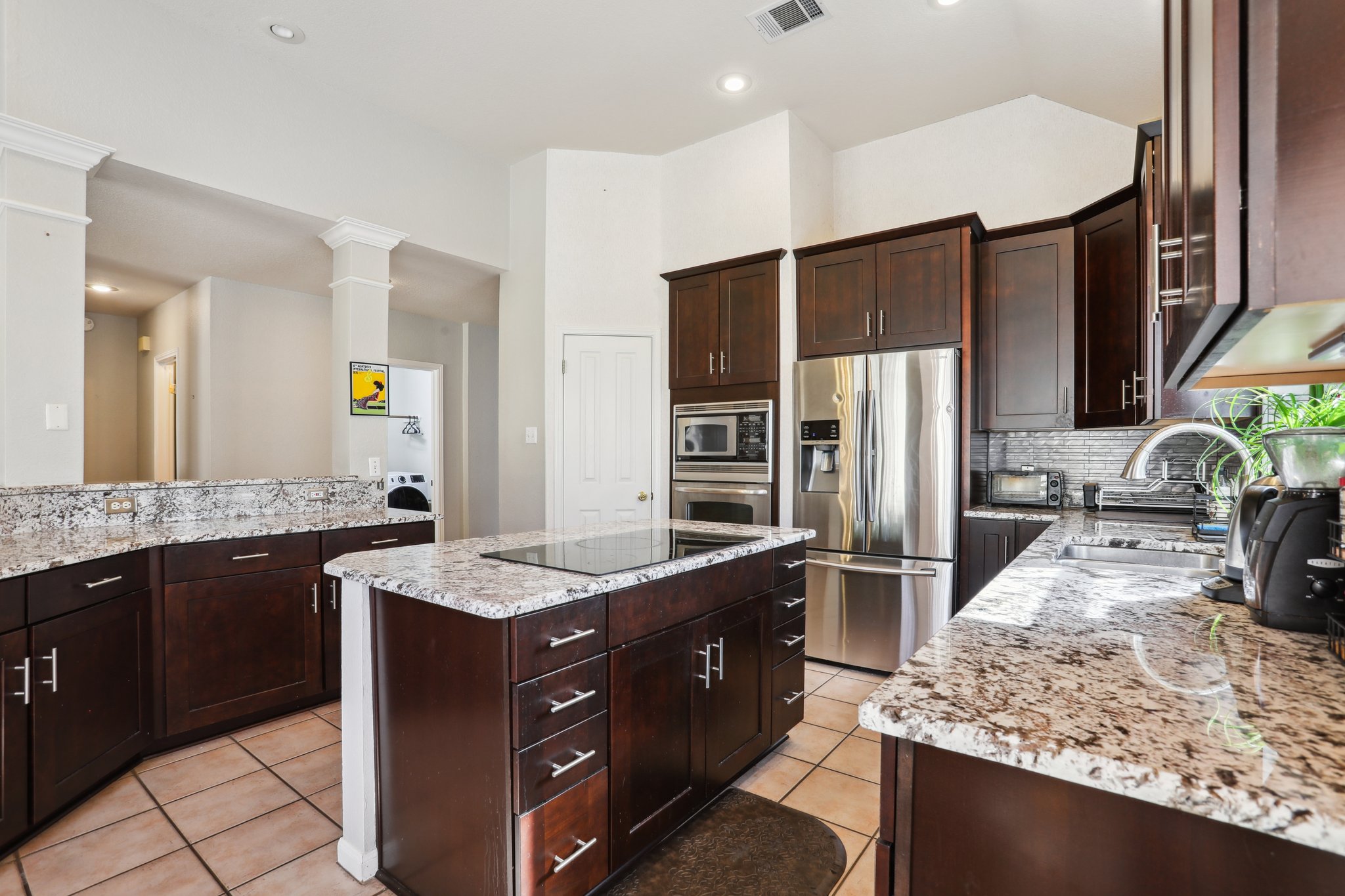 13541 Anarosa Loop Austin, TX 78727 - Photo 9 of 27 Kitchen featuring dark wood cabinetry, light granite countertops, and stainless steel appliances