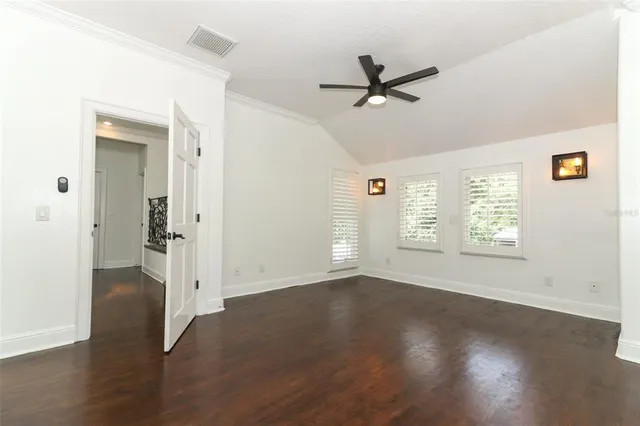 a view of an empty room with a window and hardwood floor