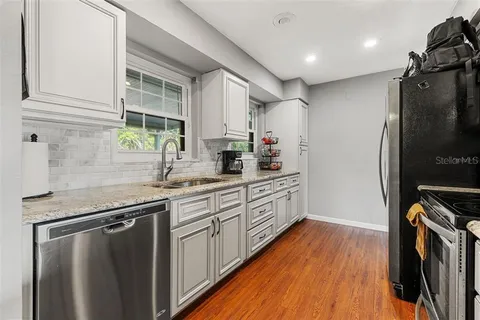 a kitchen with stainless steel appliances a refrigerator sink and wooden floor