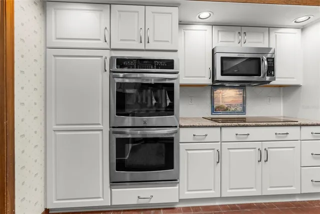 a kitchen with a refrigerator a microwave a stove and white cabinets