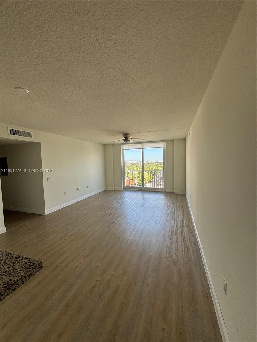 987 Southwest 37th Avenue, Unit 710 Miami, FL 33135 - Photo 2 of 6 an empty room with wooden floor and windows