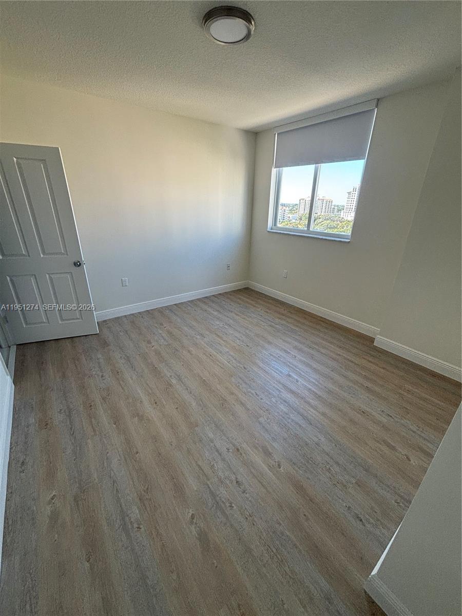 987 Southwest 37th Avenue, Unit 710 Miami, FL 33135 - Photo 4 of 6 an empty room with wooden floor and windows