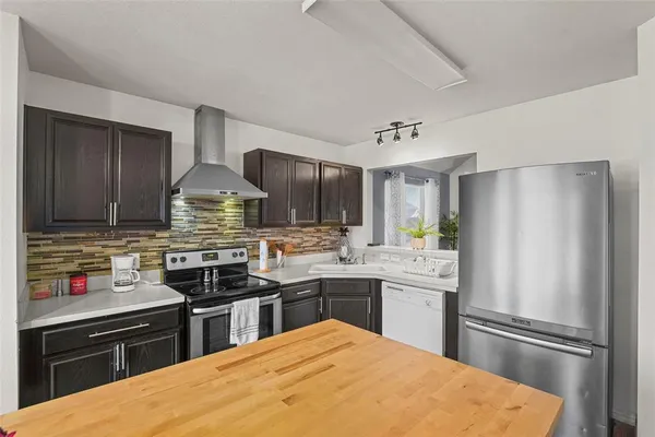 a kitchen with stainless steel appliances a sink stove refrigerator and cabinets