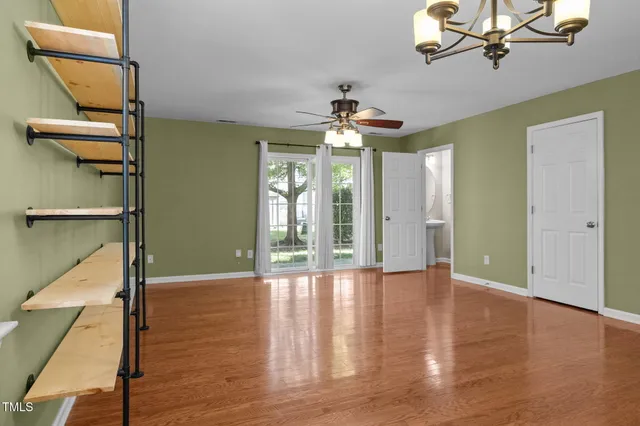 a view of an empty room with a window and wooden floor
