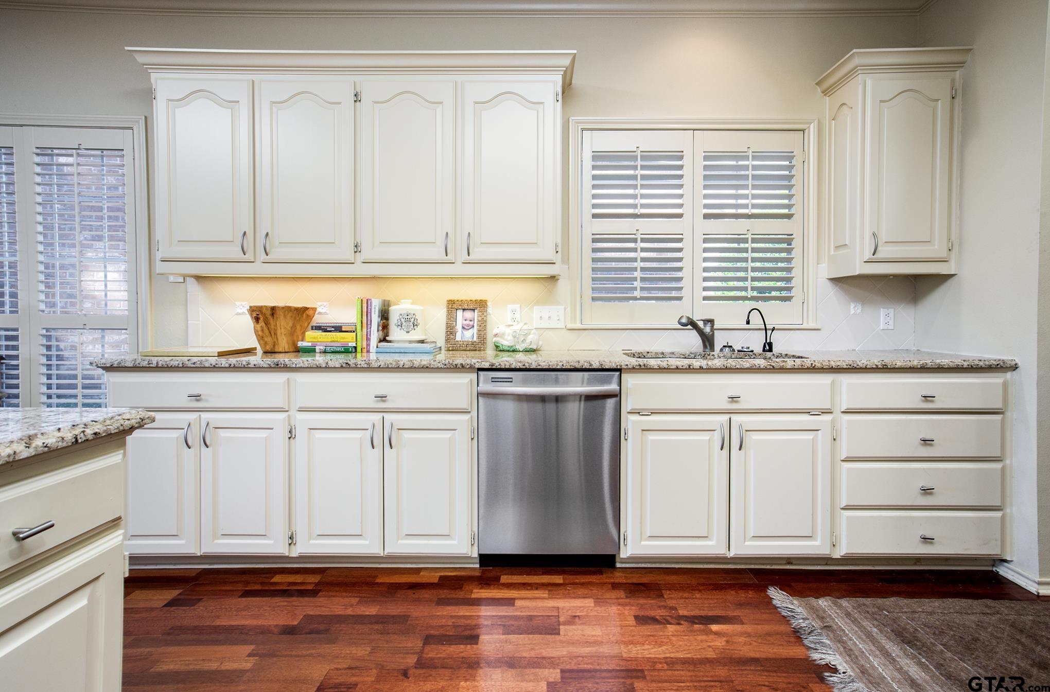 1418 Hollytree Place Tyler, TX 75703 - Photo 19 of 46 a kitchen with granite countertop a sink cabinets and wooden floors