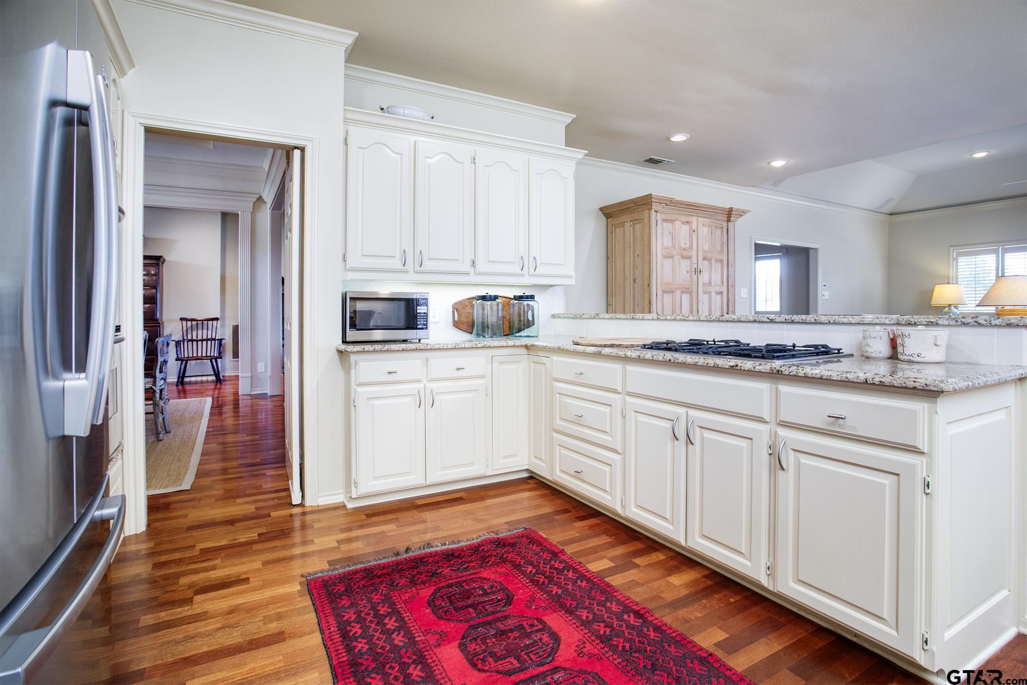 1418 Hollytree Place Tyler, TX 75703 - Photo 20 of 46 a kitchen with granite countertop a sink cabinets and wooden floor