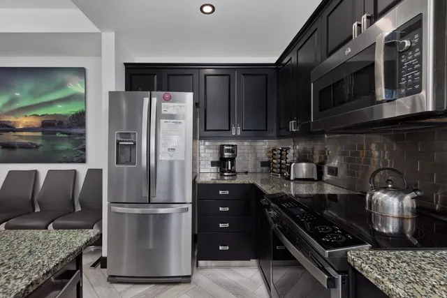 a kitchen with stainless steel appliances granite countertop a stove refrigerator and microwave