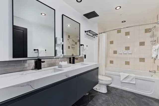 a bathroom with a double vanity sink toilet mirror and shower