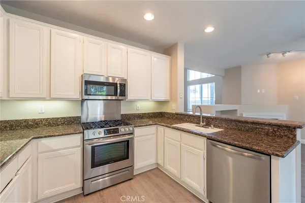 a kitchen with granite countertop a sink stove and cabinets