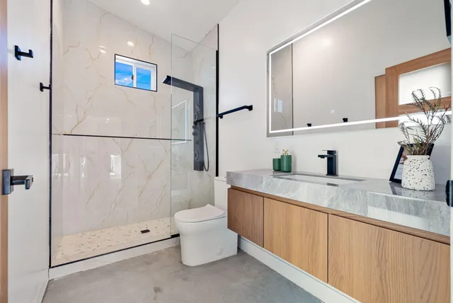 a bathroom with a granite countertop sink mirror and toilet
