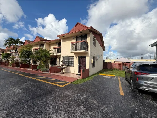 a view of multiple houses with yard and car parked