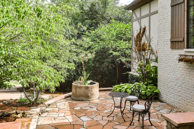 a view of a balcony with chairs potted plants and large tree