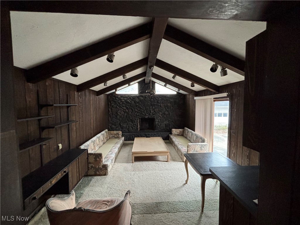 4308 Silsby Road University Heights, OH 44118 - Photo 2 of 28 Living room featuring lofted ceiling with beams, wood walls, a stone fireplace, and carpet floors