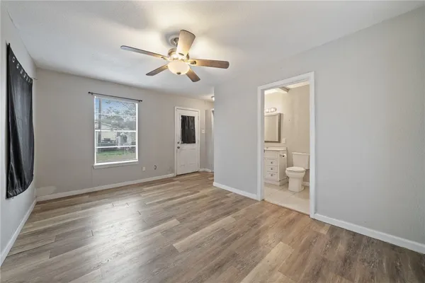 a view of empty room with wooden floor and fan