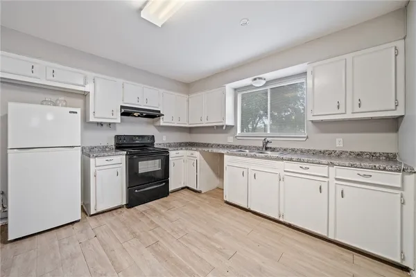 a kitchen with granite countertop white cabinets and white appliances