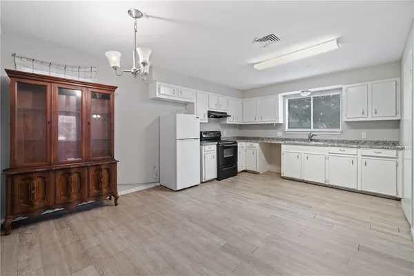 a kitchen with stainless steel appliances granite countertop a refrigerator a sink dishwasher a stove top oven a kitchen island and chairs with wooden floor