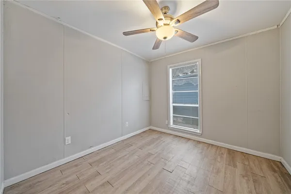 an empty room with a chandelier fan and windows
