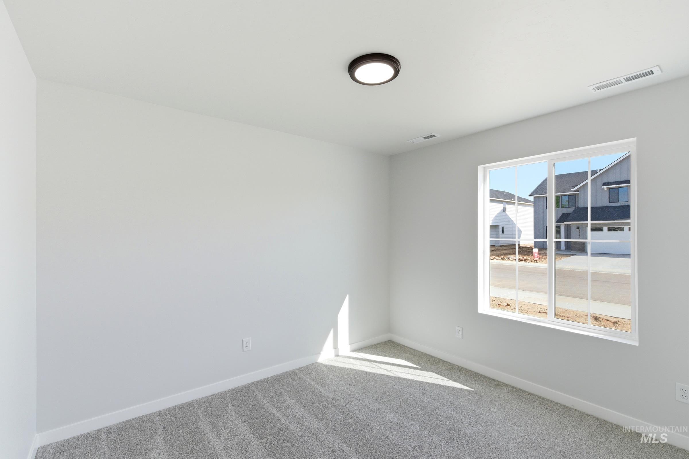 1059 West Jasper Street Meridian, ID 83642 - Photo 13 of 23 Bright interior space featuring a double-paned window, neutral wall paint, gray carpet flooring, a flush-mount ceiling light, and white baseboards