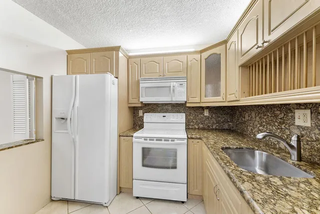 a kitchen with granite countertop a sink stove and refrigerator
