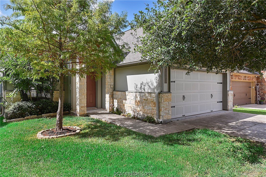 a front view of a house with a yard and large tree