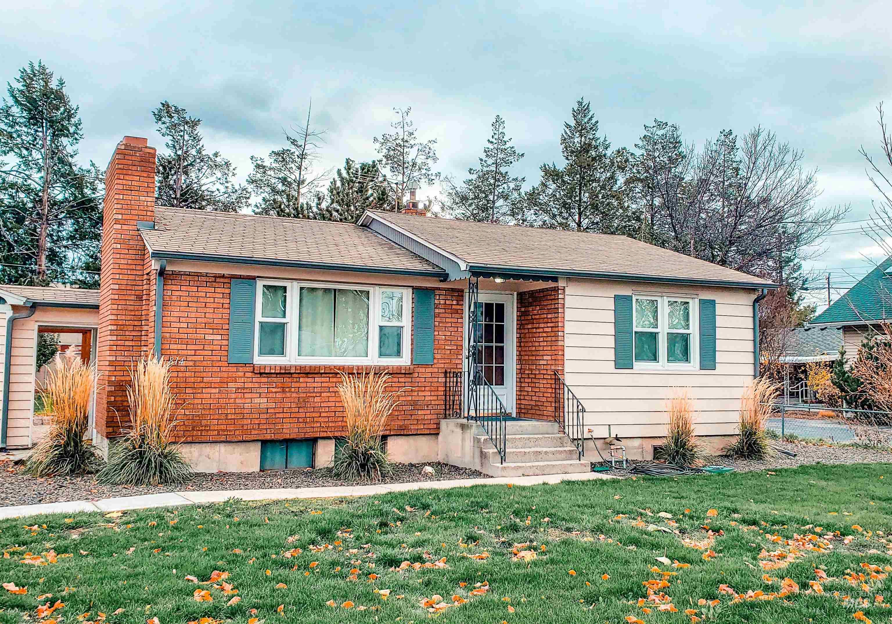 814 Baker Street Boise, ID 83706 - Photo 2 of 26 Exterior featuring a brick facade with a prominent chimney, horizontal siding, teal window shutters, concrete steps with wrought iron railings, and a shingle roof