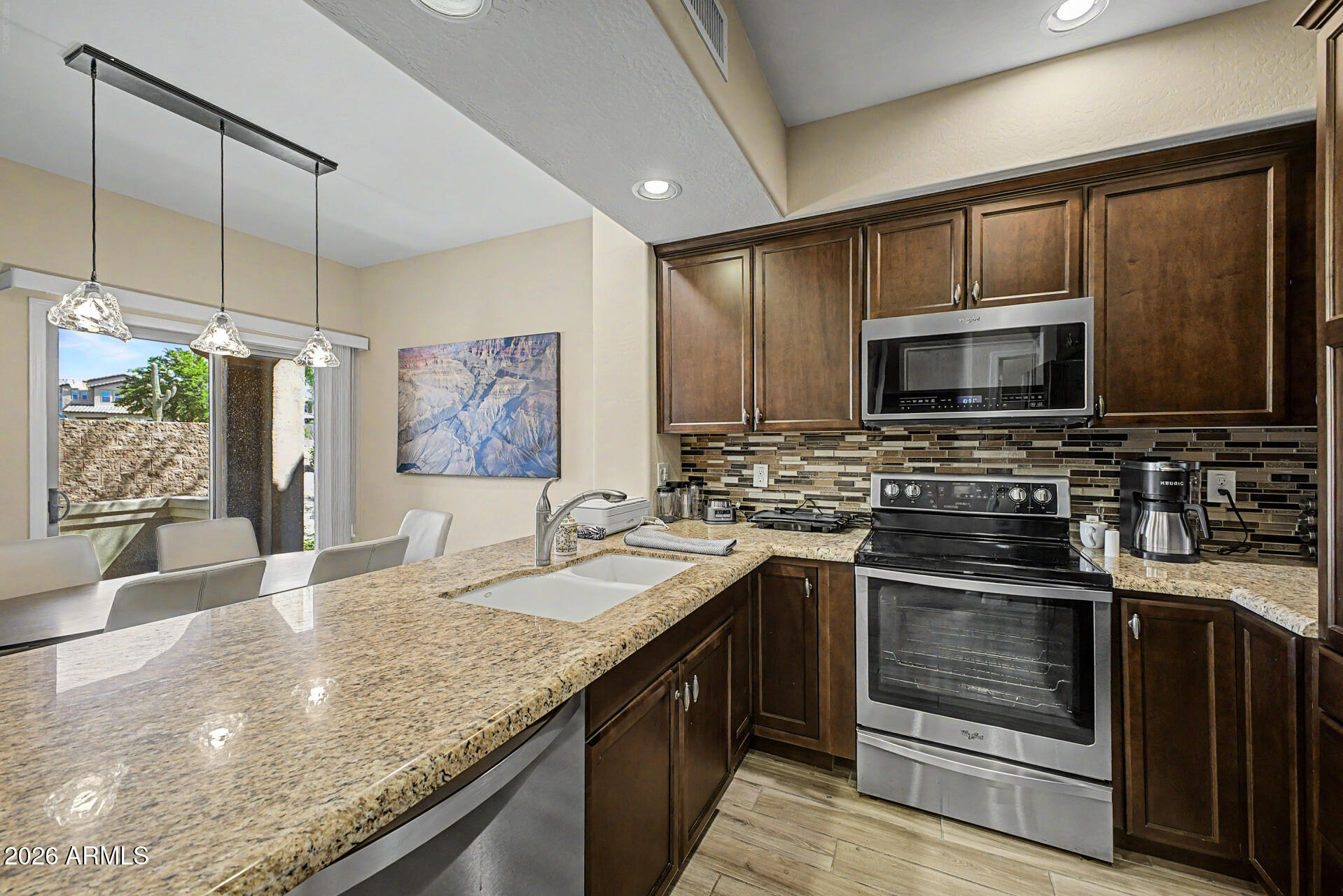3935 East Rough Rider Road, Unit 1373 Phoenix, AZ 85050 - Photo 14 of 48 a kitchen with stainless steel appliances granite countertop a sink stove and microwave