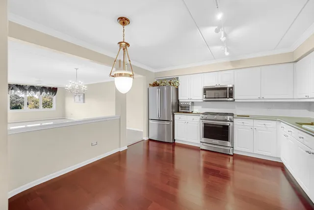 a kitchen with white cabinets stainless steel appliances and wooden floor