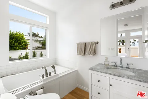 a bathroom with a granite countertop tub sink and mirror