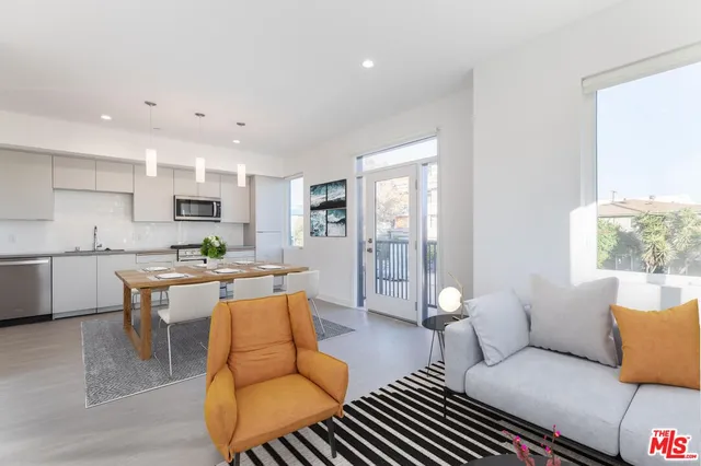 a living room with furniture a wooden floor and kitchen view