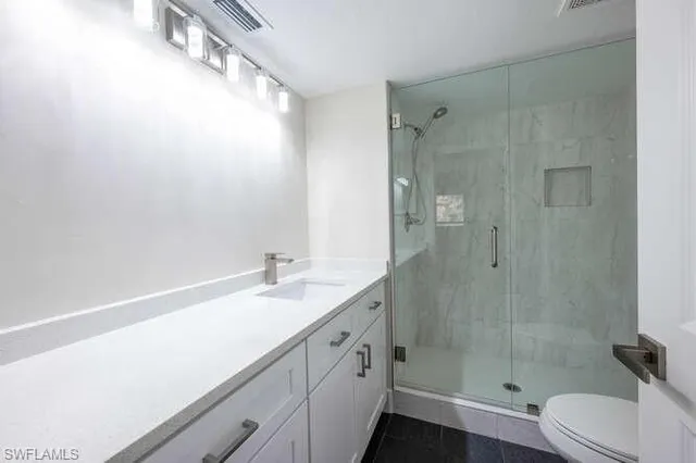a bathroom with a granite countertop sink a toilet and shower