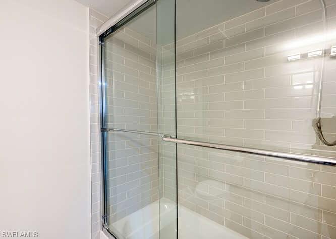 140 Cypress Way East, Unit 601 Naples, FL 34110 - Photo 20 of 27 a bathroom with a glass shower door